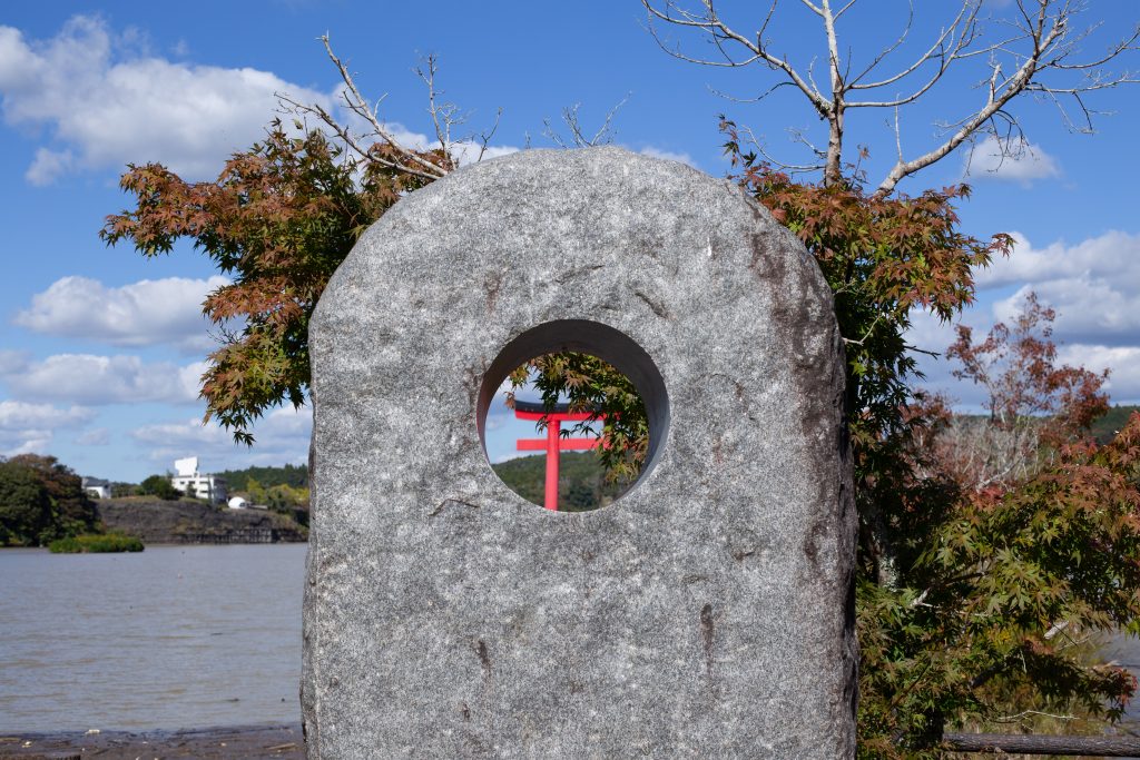 湖畔には変わった形のモニュメントが。のぞき込むとちょうど鳥居にかぶさるもみじが見え、まるで丸いフォトフレームのよう
