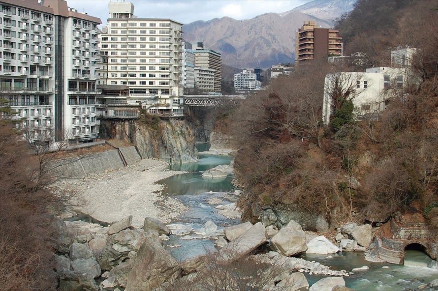 温泉街らしい景色が広がる。川沿いには日帰り温泉が楽しめるホテルも 